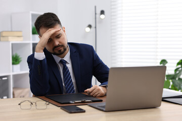 Fototapeta premium Man feeling fatigue at wooden desk in office