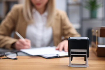 Notary working at wooden desk in office, focus on stamp