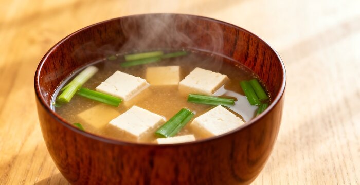 Hot Japanese miso soup with tofu and green onions in a traditional wooden bowl