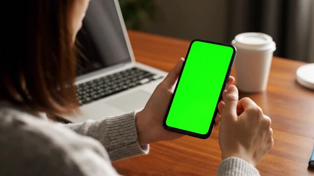 Woman interacting with a cell phone displaying a bright green keyable screen