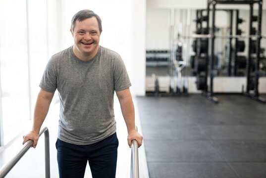 Smiling man with Down syndrome using parallel bars for a workout