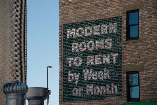 Canada, Alberta, Calgary.  Old sign advertising rooms for rent, painted on the side of brick building in the downtown core.