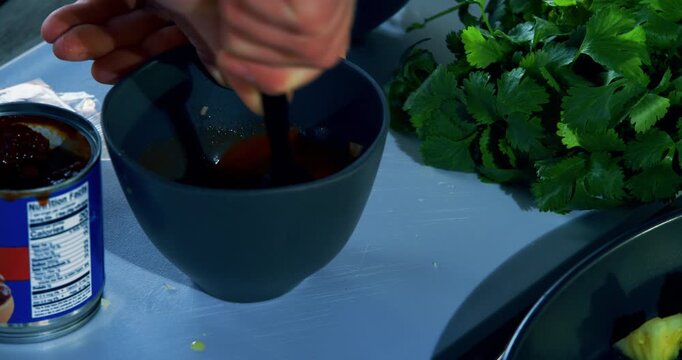 Closeup on cook stirring sauce in small bowl