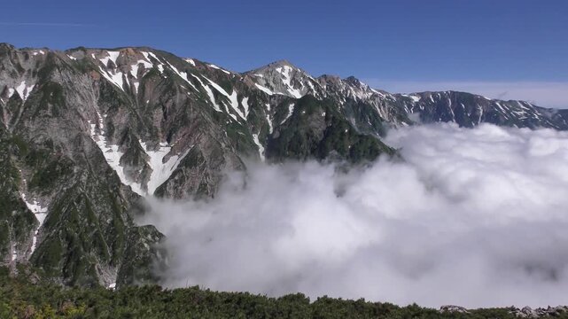 長野県白馬村の八方尾根から望む白馬三山と谷から湧き上がる雲の流れ
