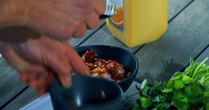 Pouring and stirring sauce into bowl of raw meat - closeup