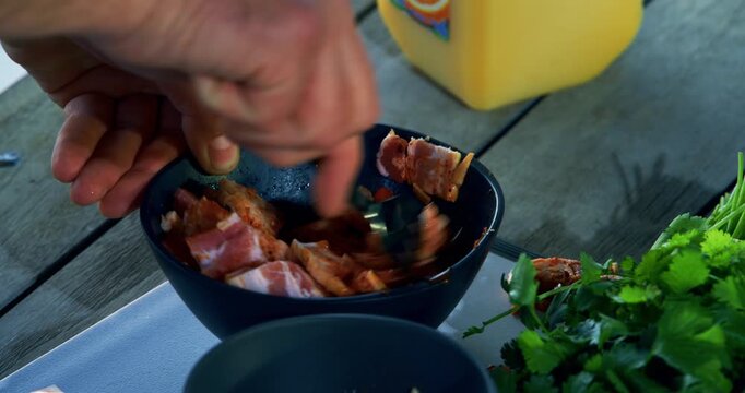 Closeup of man stirring raw meat and sauce into small bowl