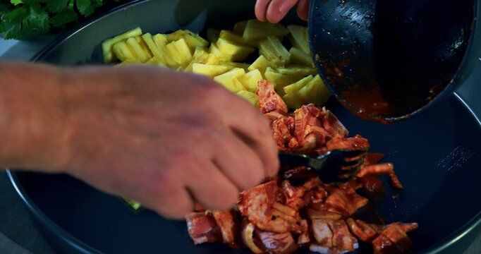 Closeup on cook's hand using fork to pull saucy meat onto plate