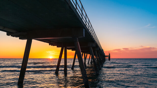 Dramatic sunset at Glenelg Beach with jetty silhouette and glowing horizon, Adelaide, South Australia