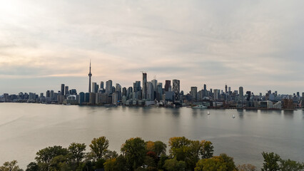 Fototapeta premium Stunning view of Toronto city skyline with lake and trees in foreground, Canada
