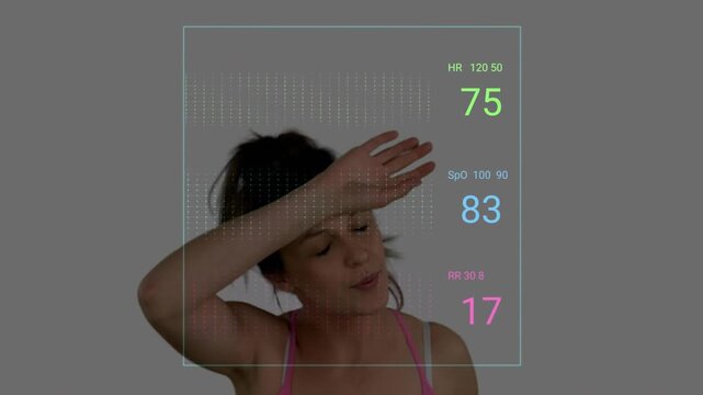 Female athlete cooling down after workout, breathing and wiping sweat, health HUD updating vitals