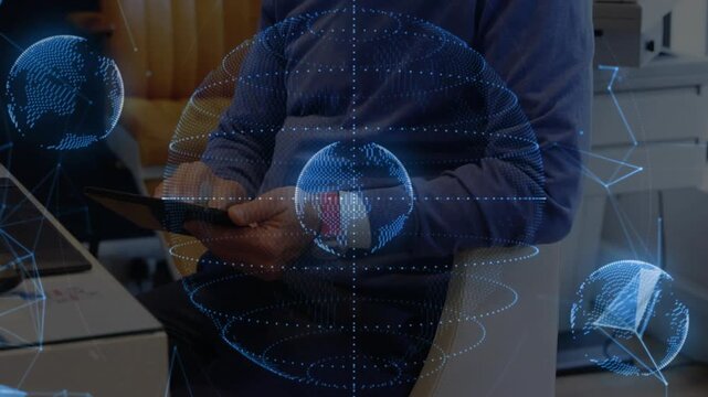 Office worker tapping tablet in office, causing holographic globes rotating over red watch for tech