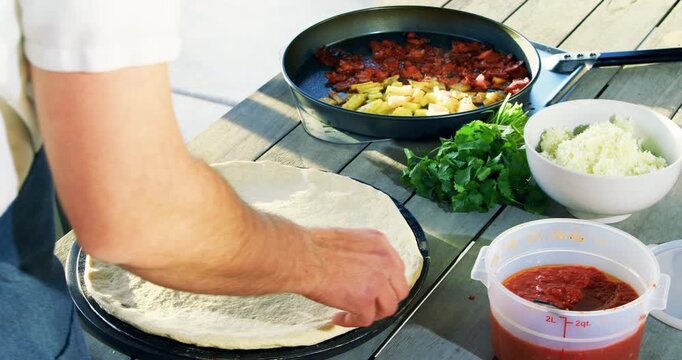 Cook with pizza dough and toppings all laid out - high, closeup shot