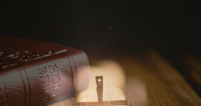 Crucifix appearing rising up as bokeh blooming, camera focusing pages fanning framing Holy Bible