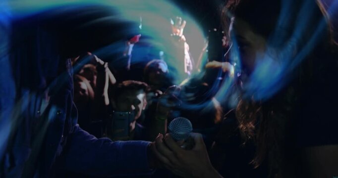 Left attendee extending arm passing sphere sharing music crowd blue swirl spiraling from sphere