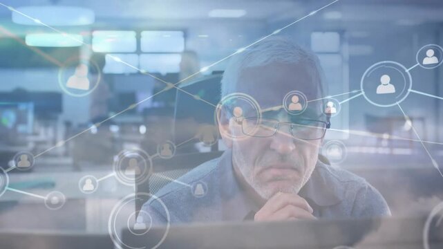 Male analyst sitting at monitor, receiving data feed and analyzing network HUD linking nodes