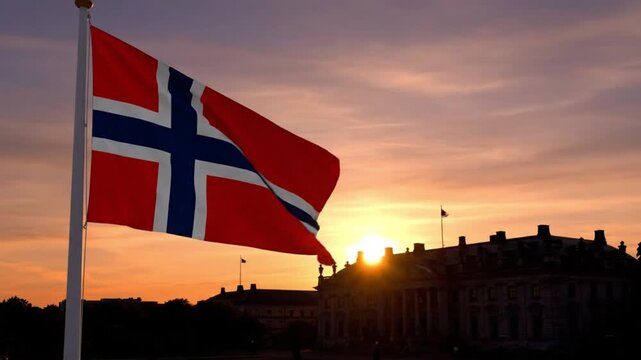 Norwegian flag waving in the wind against a vibrant sunset backdrop over a silhouette of historic buildings at dusk.