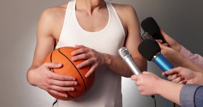 Sportsman with basketball ball giving interview to journalists on grey gradient background, closeup