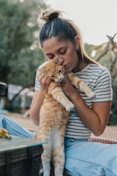 Woman hugging ginger cat showing pet affection