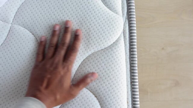 Close-up cinematic footage of person hand feeling the soft textured surface of a comfortable white mattress in slow motion, highlighting material quality and comfort