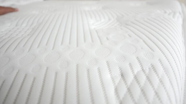 Close up of hand pressing onto memory foam mattress surface showing elastic properties and comfortable texture