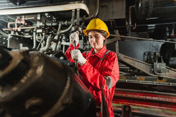 woman in a red and white jumpsuit is working on a train engine