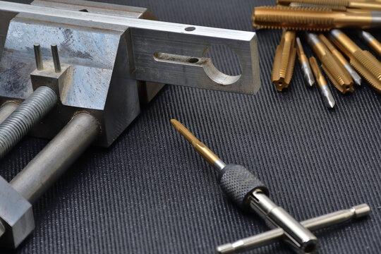 Threading tool in action on a aluminum piece. Tapping tool to create thread. Metal tap and drive handle. Hand threading tool.