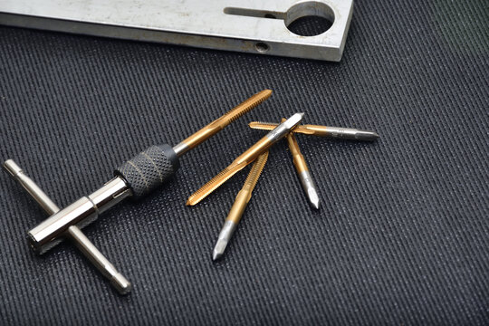 Threading tool in action on a aluminum piece. Tapping tool to create thread. Metal tap and drive handle. Hand threading tool.