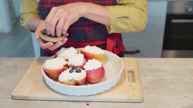 4K close-up video woman cooking beaked apples with cotage cheese decorating with blueberry homemade baking process Fresh ingredients, healthy food nutritious dessert, cooking at home nutrition concept