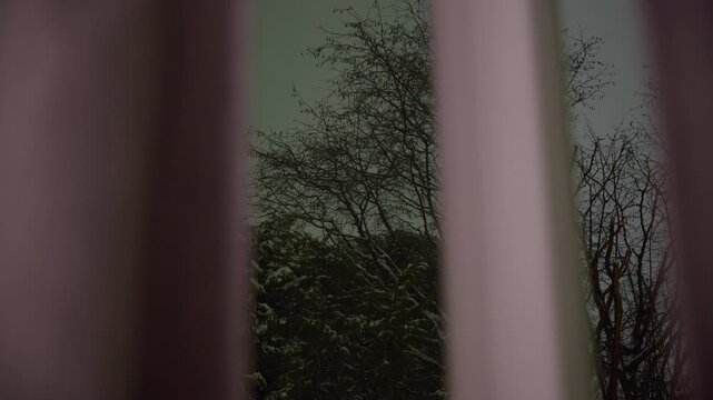 Camera looks through the curtains and out to the dark night on a cold winter day in Norway