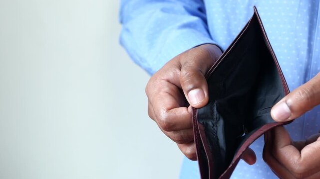 Man holding empty wallet showing no money, concept of poverty or financial problems