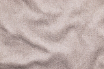 Wrinkled light brown woven linen texture with soft wavy folds, crumpled fabric with copy space