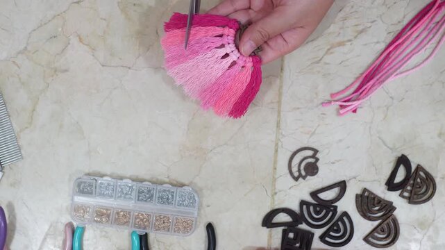 Female hands making earrings with macrame thread