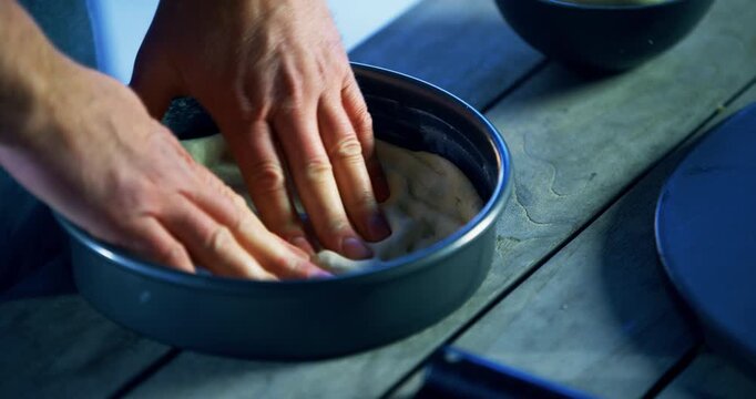 Man's hands turning pan and patting down pizza dough - high shot