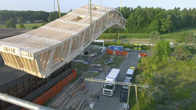 Crane lifting large wooden bridge structure into place for construction project