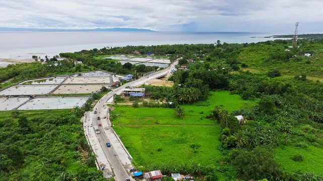 Establishing aerial shot of tropical highway beside aquaculture ponds Cebu