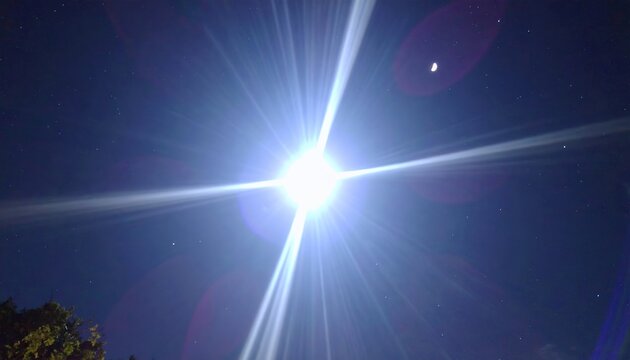Brillante destello de luz blanca intenso con efecto cruz y destellos &oacute;pticos contra el cielo nocturno oscuro.