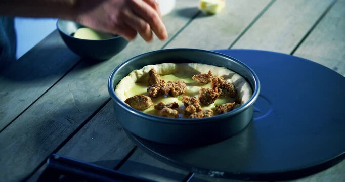 Meat and cheese being placed in pan with pizza dough - closeup