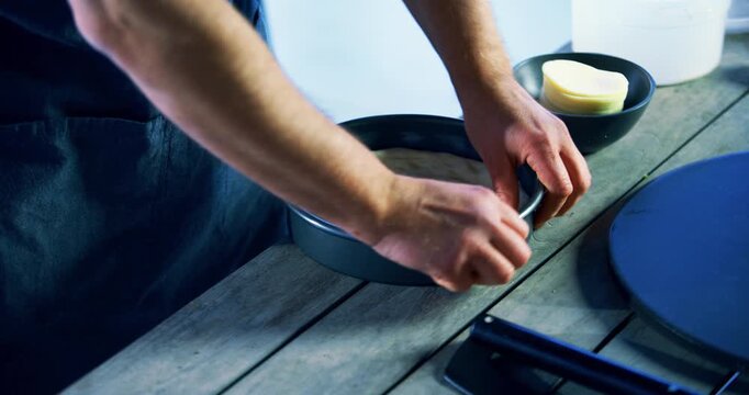 Cook patting pizza dough down in pan then spreading cheese slices inside it
