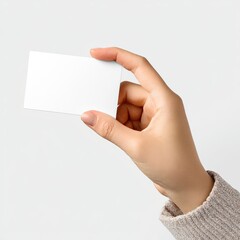 Obraz premium Close-up of a hand holding a blank white rectangular card, against a light backdrop