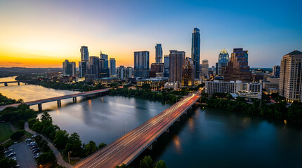 Obraz premium Downtown Skyline at Sunset with River and Highway Light Trails – Urban Growth and Waterfront Living Concept