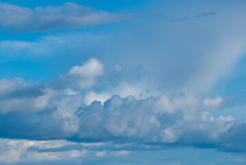 White fluffy clouds scattered across a bright blue sky with soft sunlight illuminating the scene, creating a serene and tranquil atmosphere in the sky