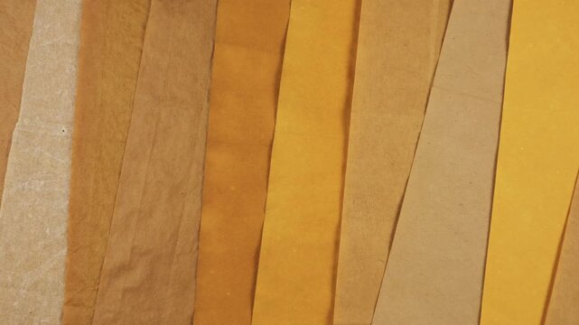 Warm natural handmade paper background with shades of yellow, orange, and brown. The eco-friendly recycled material showcases a beautiful grunge texture for creative projects.