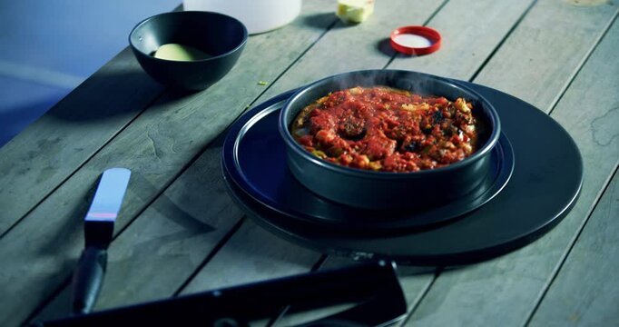 Large spatula dropping steaming saucy meal in tray - high, closeup shot