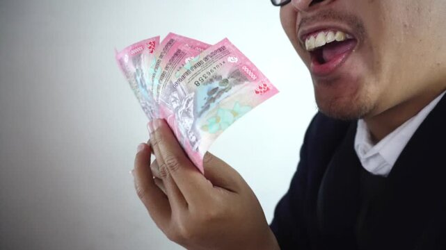 Close up of a man fanning rupiah money in front of his face. Copy space, Promotion, Marketing