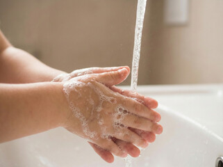 Fototapeta premium child washing hands with soap at home bathroom representing parenting education hygiene habits and healthy lifestyle awareness campaign concept