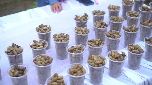 Boiled peanuts are placed in plastic cups one by one. Ready to be sold