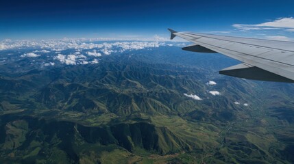 Naklejka premium Airplane wing soaring above vast mountain ranges and cloudy blue skies