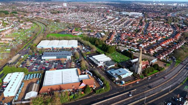 aerial drone shot high angle over the Millbrook suburban housing area estate in Southampton at sunset with trees, homes and nature surrounding. Shot in winter with traffic and cars driving the streets