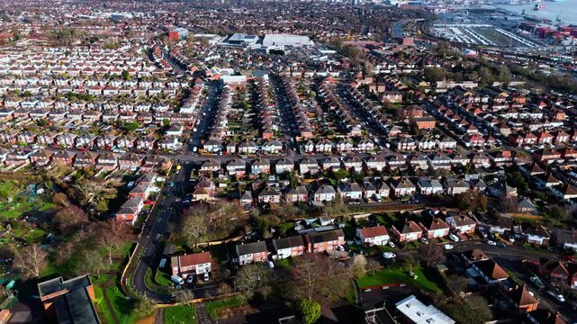 aerial drone shot high angle over the Millbrook suburban housing area estate in Southampton at sunset with trees, homes and nature surrounding. Shot in winter with traffic and cars driving the streets
