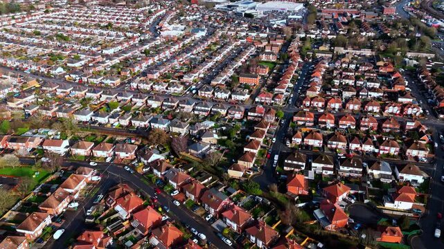 aerial drone shot high angle over the Millbrook suburban housing area estate in Southampton at sunset with trees, homes and nature surrounding. Shot in winter with traffic and cars driving the streets
